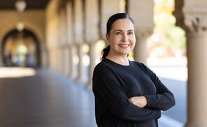 Angela Garcia stands with arms crossed wearing a black sweater with her dark hair pulled back in a pony tail