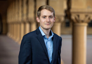 Photo of Ben Moran wearing a light-blue collared shirt and a dark-blue jacket