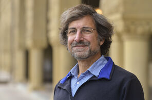 Rafe Mazzeo wearing glasses and a navy-blue zip-up sweater over a light-blue collared shirt. His sweater is unzipped at his sternum and folded down to reveal a royal-blue collar.