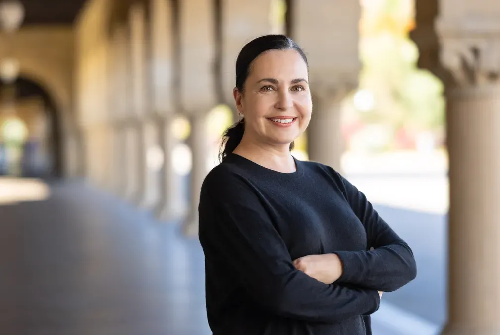 Angela Garcia stands with arms crossed wearing a black sweater with her dark hair pulled back in a pony tail