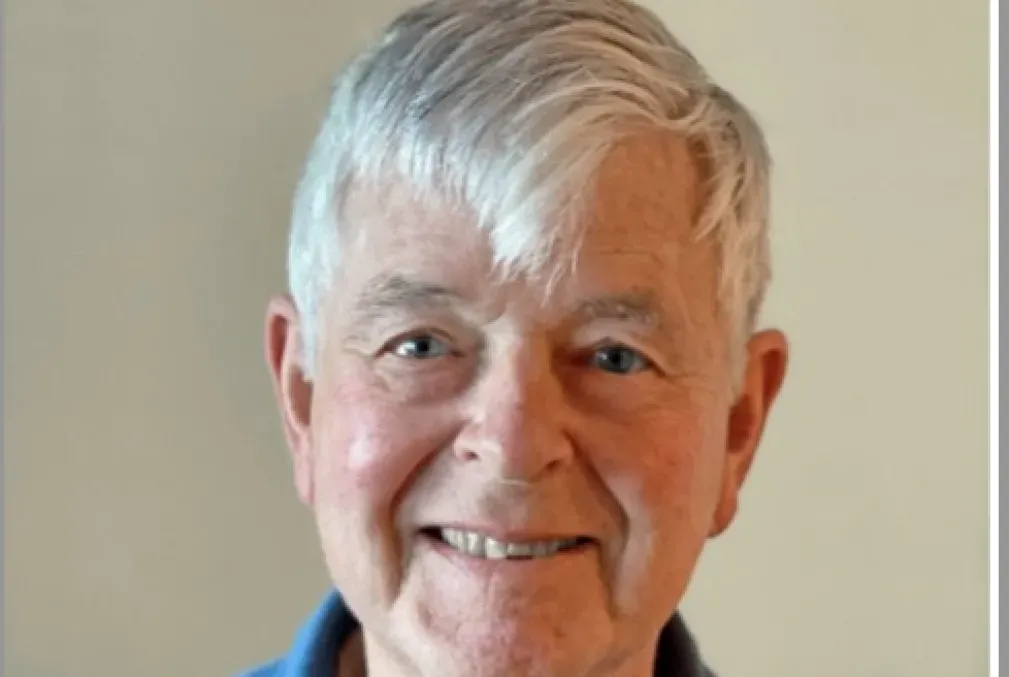 George Collier smiling and wearing a blue polo shirt